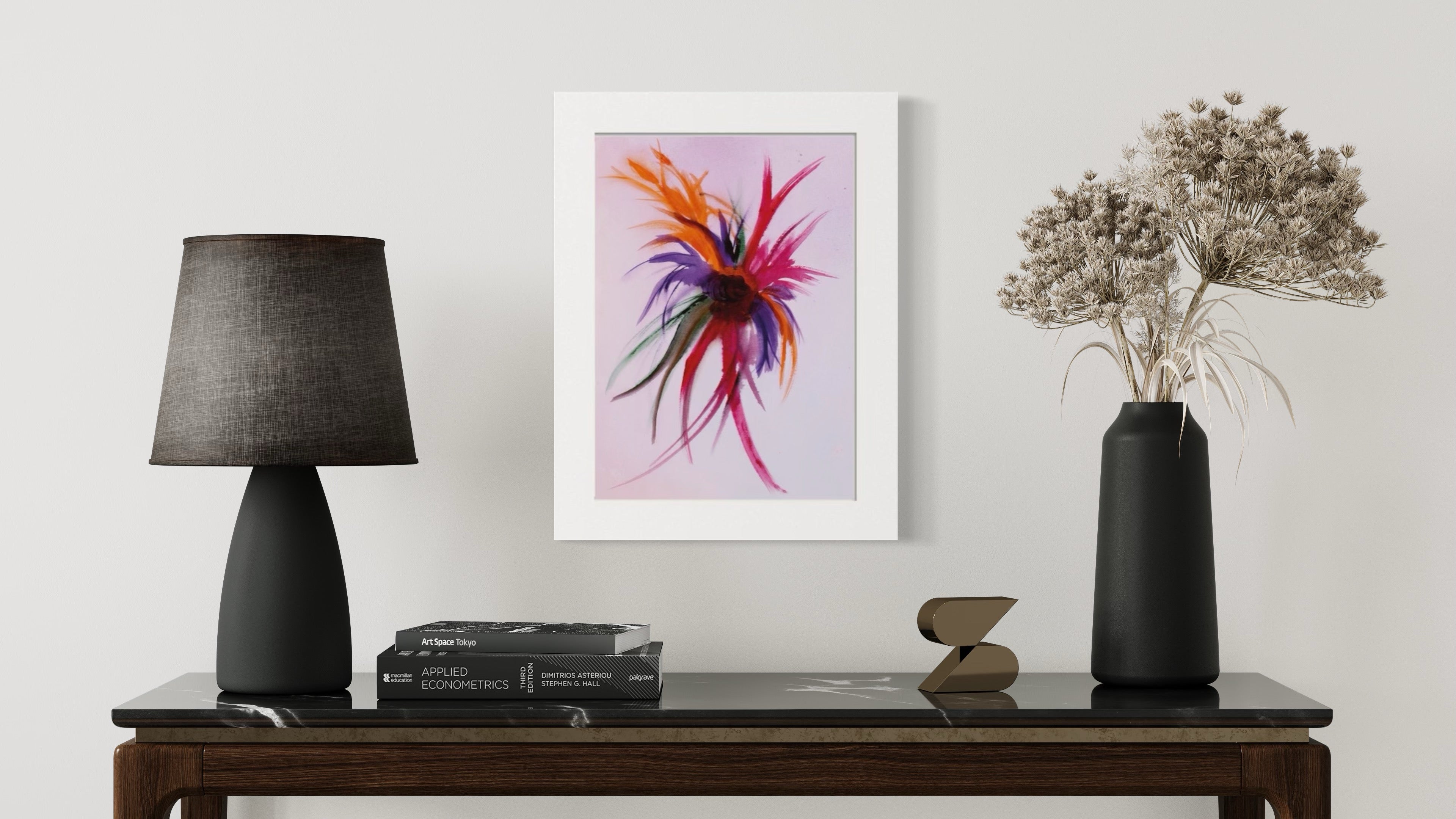 Framed abstract artwork on a wall above a table with decorative items.